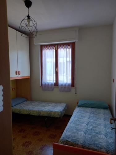 een kamer met 2 bedden en een raam bij Via del tombolo in Grosseto