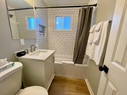 La salle de bains blanche est pourvue d'un lavabo et d'une baignoire. dans l'établissement Cathedral View 10-Cozy Urban Living Near UNMC, à Omaha
