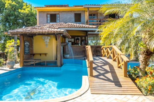 uma casa com uma piscina e um deque em Pousada Das Araras em Itaúnas