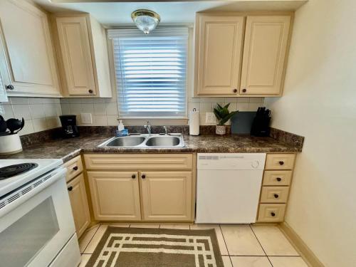 a kitchen with white cabinets and a sink and a window at Cathedral 11-Midtown near UNMC in Omaha