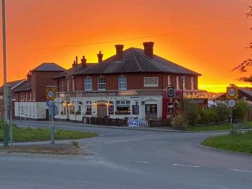 um edifício ao lado de uma rua com um pôr-do-sol em Stonehenge Inn & Shepherd's Huts em Amesbury