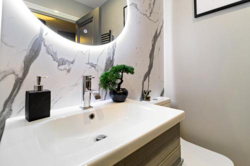 La salle de bains est pourvue d'un lavabo blanc et d'un miroir. dans l'établissement WhiskAwayStays - Victoria House - Apartment 3, à Worcester