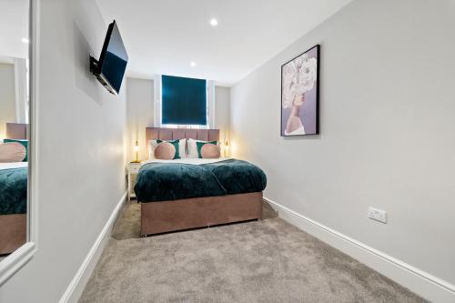 a bedroom with a bed and a tv on a wall at WhiskAwayStays - Victoria House - Apartment 3 in Worcester