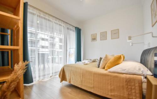 a bedroom with a bed and a large window at Apartamenty Na Wyspie - Baltic Park - Apartamenty z sypialnią i parkingiem - ul Uzdrowiskowa 24-34 in Świnoujście