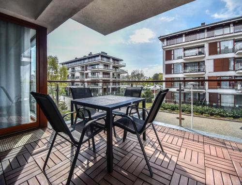 a patio with a table and chairs on a balcony at Apartamenty Na Wyspie - Baltic Park - Apartamenty z sypialnią i parkingiem - ul Uzdrowiskowa 24-34 in Świnoujście