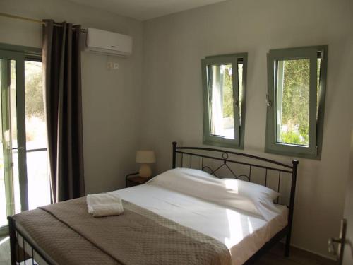ein Schlafzimmer mit einem Bett und zwei Fenstern in der Unterkunft Casa Cimara in Kefalonia