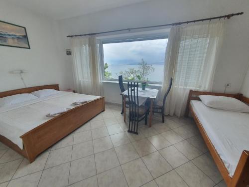 ein Schlafzimmer mit zwei Betten und einem Tisch und einem Fenster in der Unterkunft Apartments - Buffet 2B in Sveti Juraj