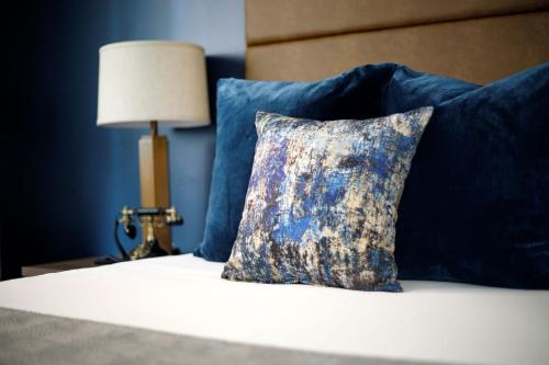 a pillow on a bed with blue pillows and a lamp at Hotel at Old Town in Wichita
