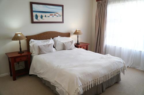 Schlafzimmer mit einem Bett mit weißer Bettwäsche und Kissen in der Unterkunft Pinnacle Point Golf Estate Lodge 78 in Mossel Bay