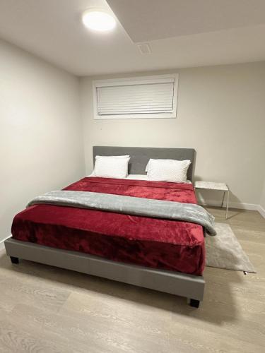 1 dormitorio con 1 cama con manta roja en Open modern concept 2BR basement, en Calgary