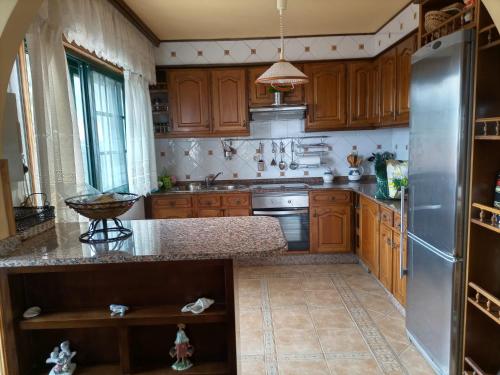 a kitchen with wooden cabinets and a stainless steel refrigerator at Chalet con vistas al mar en la playa de A Lanzada in O Grove