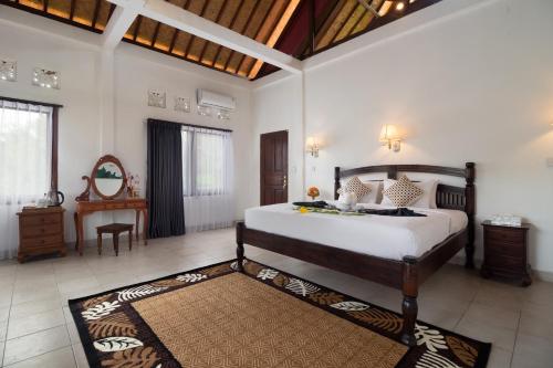 a bedroom with a large bed in a room with a table at The Kanjeng Signature Sidemen in Sidemen
