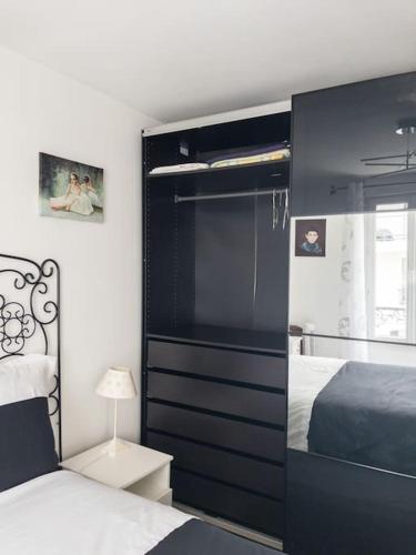 een slaapkamer met een bed en een grote zwarte kast bij Un parfait chez soi à Puteaux in Puteaux