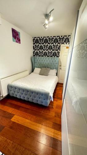 a small bedroom with a bed with a blue headboard at Eastbury Road Home in Watford