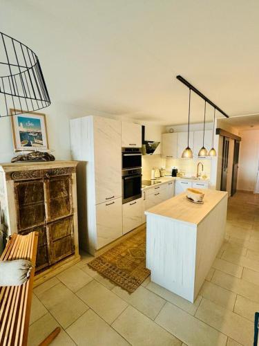 une cuisine avec des armoires blanches et une table à l'intérieur dans l'établissement Résidence la Corniche appartement rénové de 66m2 pleine vue mer!, à Sète