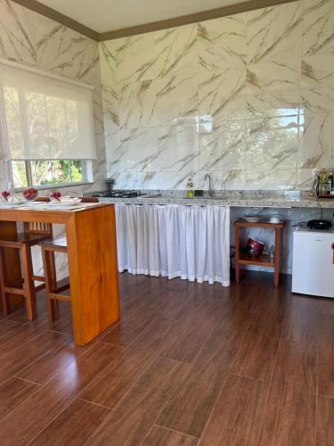 a kitchen with a counter with white curtains at Chales Maria Flor in Gonçalves