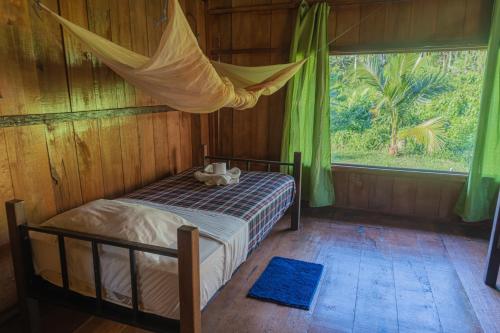 Kichwa Lodge في Aguarico: غرفة نوم بسرير مع ناموسية