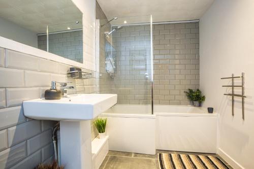 a bathroom with a sink and a tub and a shower at Beach haven retreat, Caswell Bay in Swansea