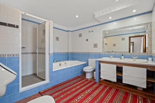 bagno blu con vasca, lavandino e servizi igienici di Casa El Tarajal a Málaga