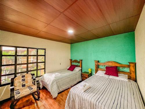 two beds in a room with green walls at Paraíso en Atitlán in Panaranjo