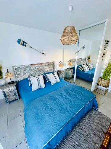 une chambre avec un lit bleu et un miroir dans l'établissement Résidence la Corniche appartement rénové de 66m2 pleine vue mer!, à Sète