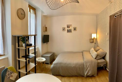 - une chambre avec un lit, une chaise et un réveil dans l'établissement Cosy appartement centre ville parking Netflix, à Montluçon