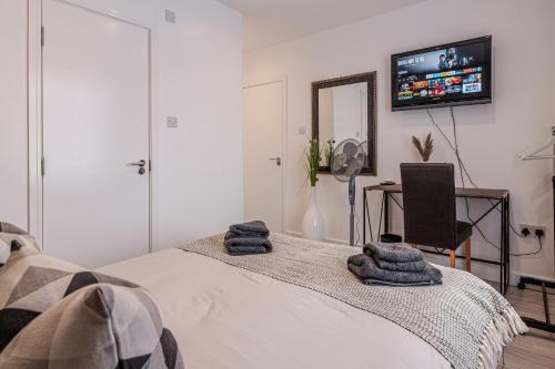 a bedroom with a bed and a tv on the wall at Stunning Ensuite Room in Beckenham