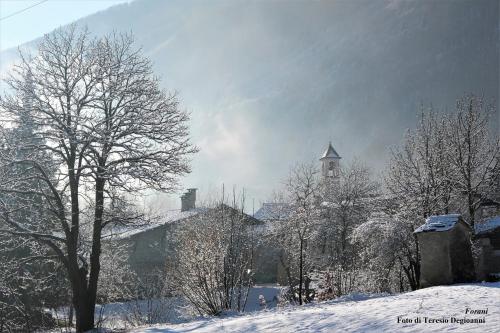 una ciudad cubierta de nieve con una iglesia y una torre en Il Fontanile, en Aisone