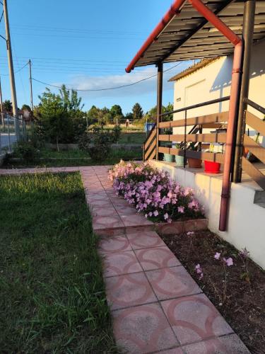 a stone walkway in front of a house with flowers at Johnny 's private house in Néa Michanióna