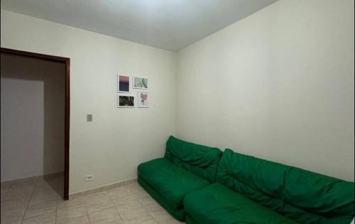 a living room with a green couch in the corner at Apartamento pé na areia de frente para o mar in Mongaguá