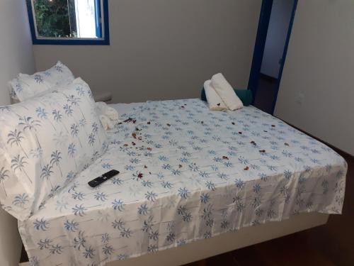 a bed with a white comforter with a remote control on it at Espaço Solar do Carmo in Mariana