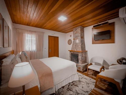 a bedroom with a white bed and a fireplace at La Bella Monte Verde in Monte Verde