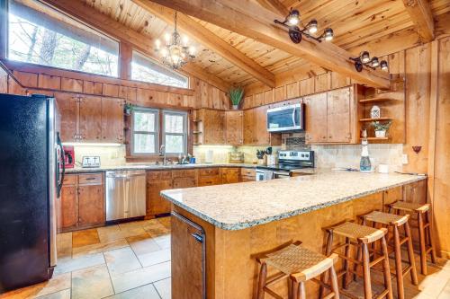 a large kitchen with wooden cabinets and a black refrigerator at Treehouse-Style Cabin, 1 Mi to Massanutten Resort in McGaheysville