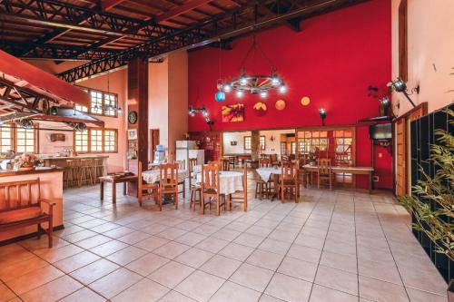 a restaurant with a red wall and tables and chairs at Chácara Nosso Sonho in Atibaia
