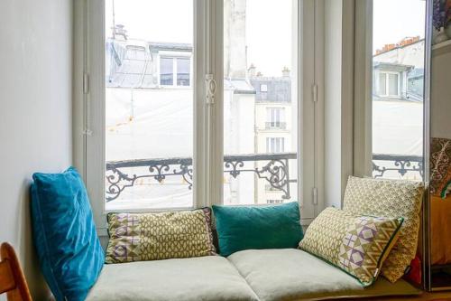 un canapé installé devant une grande fenêtre dans l'établissement Superbe appartement lumineux proche du Marais, à Paris
