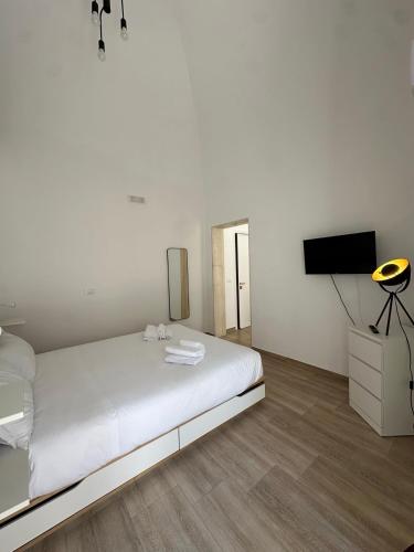 a white bedroom with a bed and a flat screen tv at Casa Garruba 99 in Bari