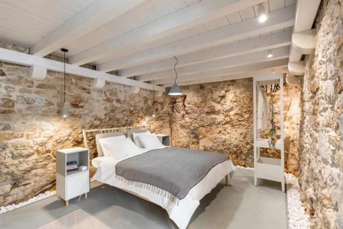 ein Schlafzimmer mit einer Steinwand und einem Bett in der Unterkunft Casa Cava in Pučišća