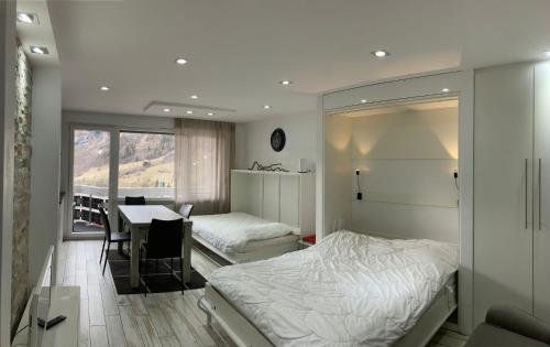 um quarto com 2 camas e uma mesa e uma mesa e cadeiras em Flaminia Wohnung 15 - Best view and Free parking! em Leukerbad