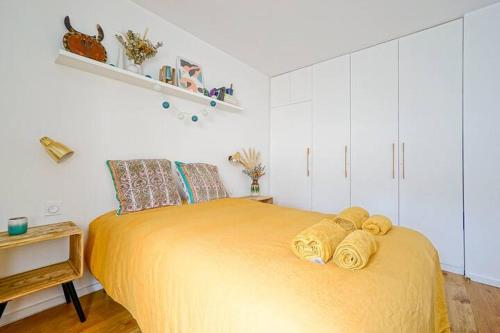 - une chambre dotée d'un grand lit avec des draps jaunes dans l'établissement Superbe appartement lumineux proche du Marais, à Paris