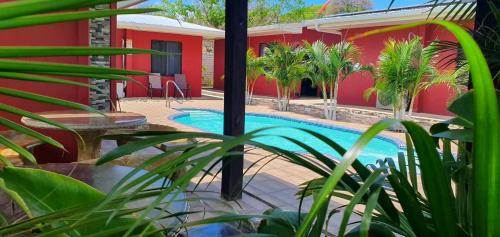 una piscina con palmeras y un edificio rojo en Villas Bahía Salinas, en La Cruz