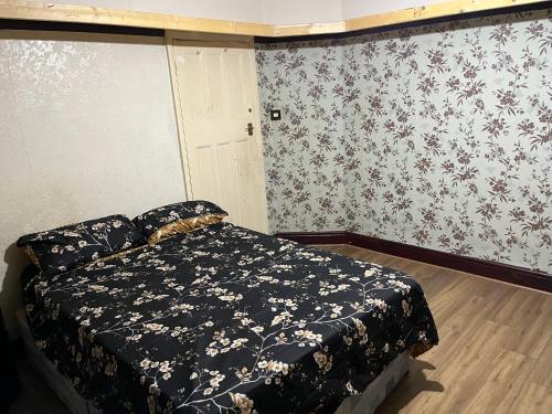 Leicester UK Fosse Park Shopping Centre Room 2 في Braunstone: غرفة نوم مع سرير في غرفة مع ورق جدران زجاجي