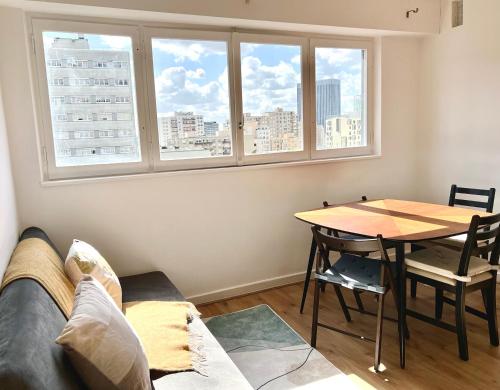 a living room with a couch and a table and windows at Confortable et Chic Appartement in Courbevoie