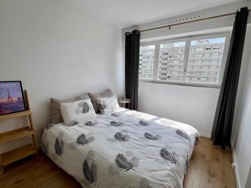 a bedroom with a bed and a large window at Confortable et Chic Appartement in Courbevoie