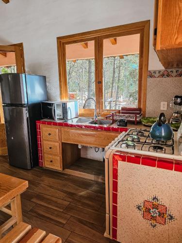 a kitchen with a refrigerator and a stove top oven at BACANA CABAÑAS DE ALQUILER in Mazamitla