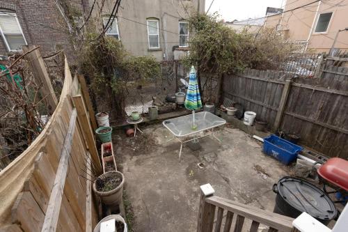 a garden with an umbrella in a backyard with a fence at 3-Bed Luxurious Home Close to NYC in Jersey City