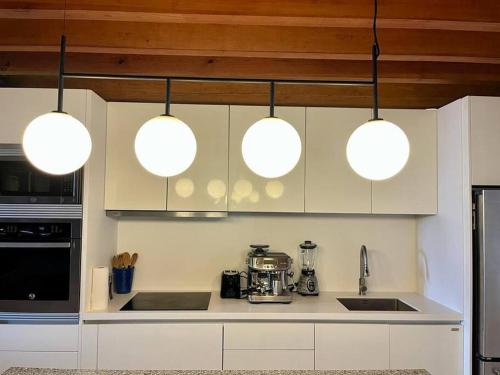 a kitchen with three lights hanging over a counter at Ocean Front Luxury - 5 Pools & Private Beach Club in Careyes
