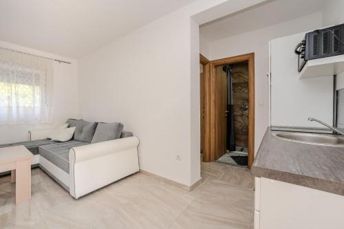 a white living room with a couch and a kitchen at Apartments and Rooms STIPANOVI DVORI in Donji Karin