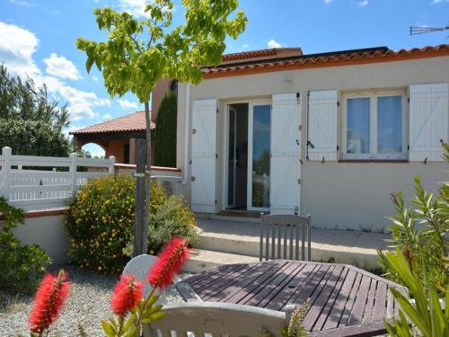 una casa con una recinzione bianca e un tavolo di fronte di Maison avec 2 terrasses à 400 mètres de la plage a Le Barcarès