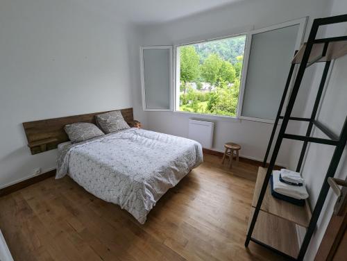 um quarto com uma cama e uma grande janela em Maison rénovée sur Laruns em Laruns