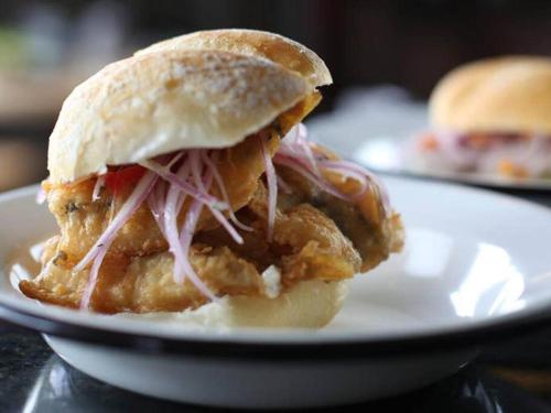 a chicken sandwich on a plate on a table at Groën Chincha® Casa de Campo centrica y turistica in San Pedro